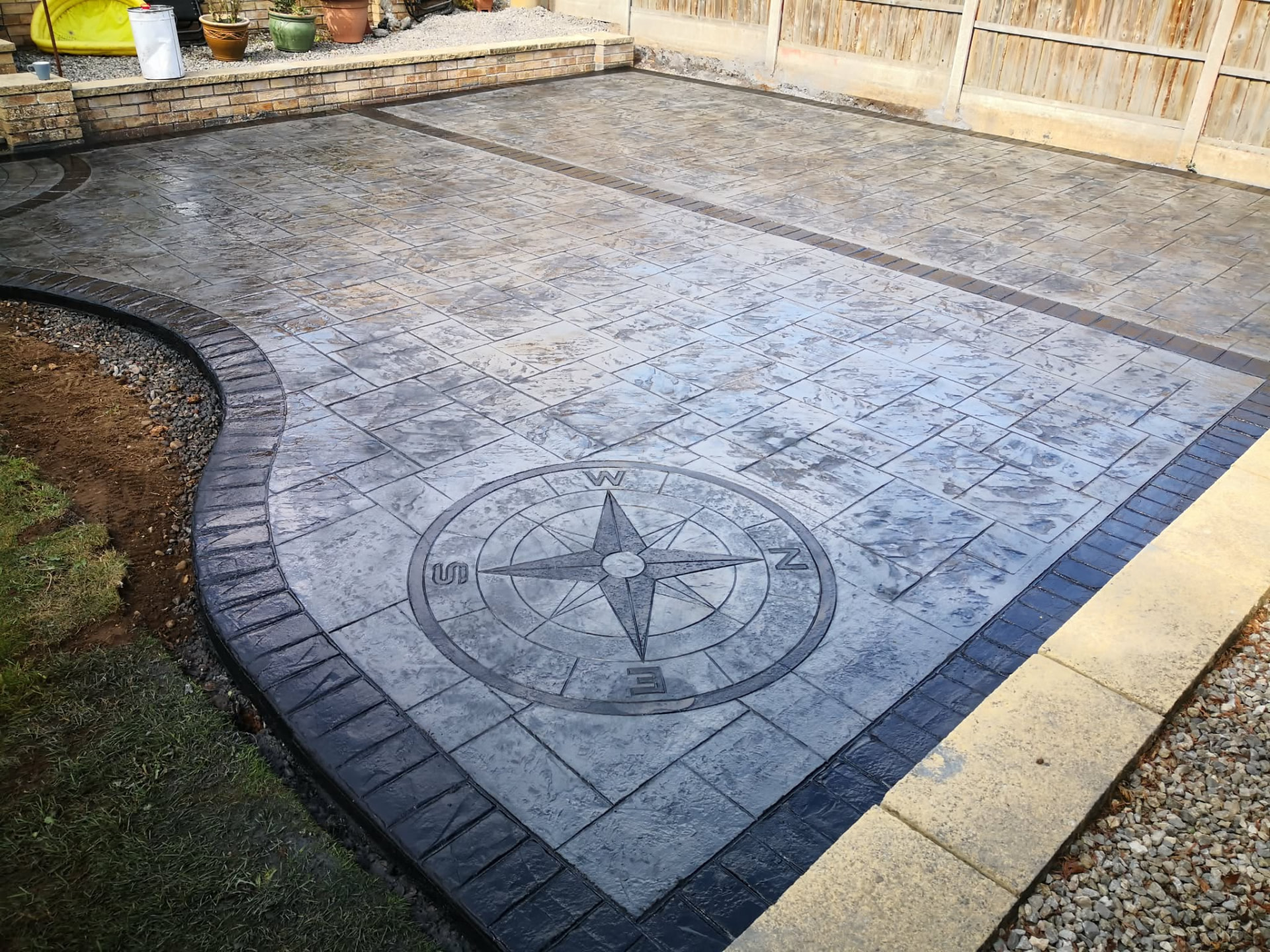 Grey imprinted concrete patio with a detailed compass inlay