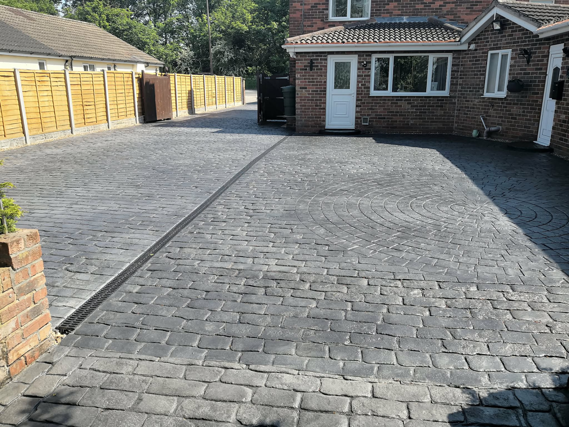 Grey cobble effect pattern imprinted concrete driveway with a linear drainage channel