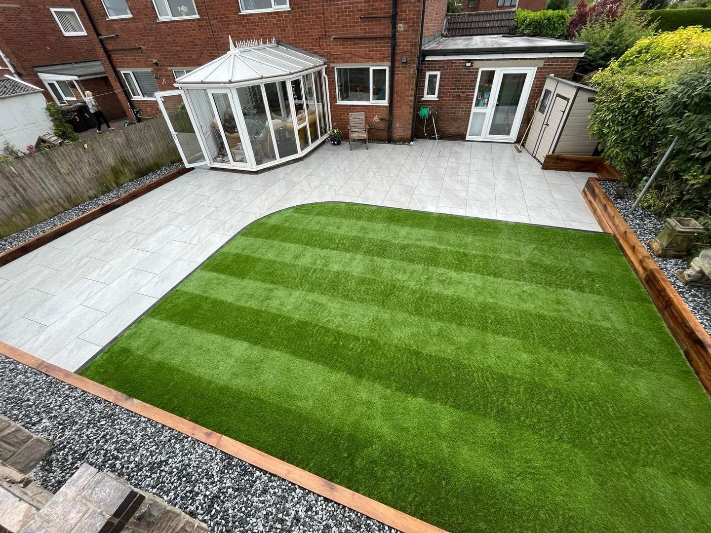 Light grey porcelain patio with striped artificial grass lawn and sleeper edging