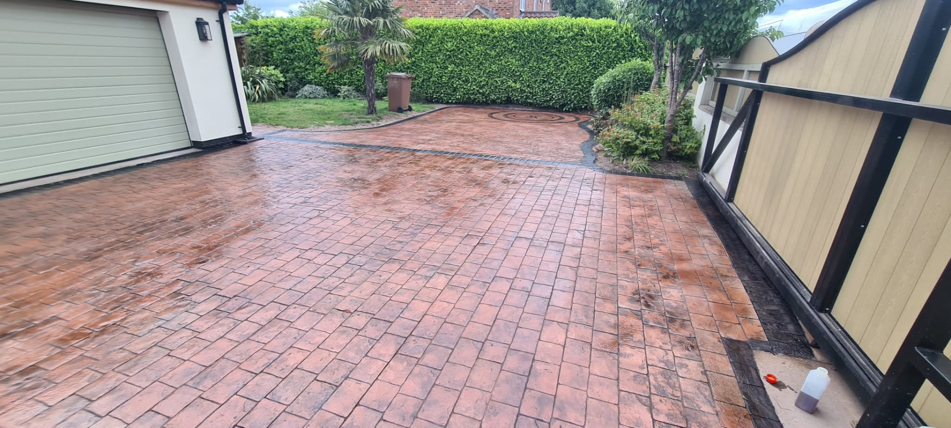 Red-brown pattern imprinted concrete driveway outside a home